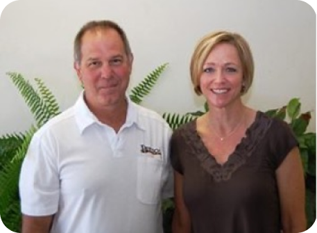 Tim and Stacey Bertsch stand in front of indoor plants facing the camera